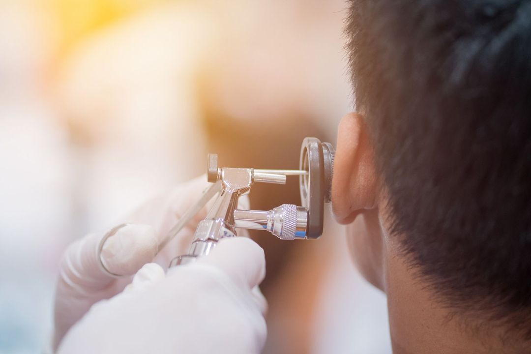Un hombre se está haciendo examinar el oído por un médico.