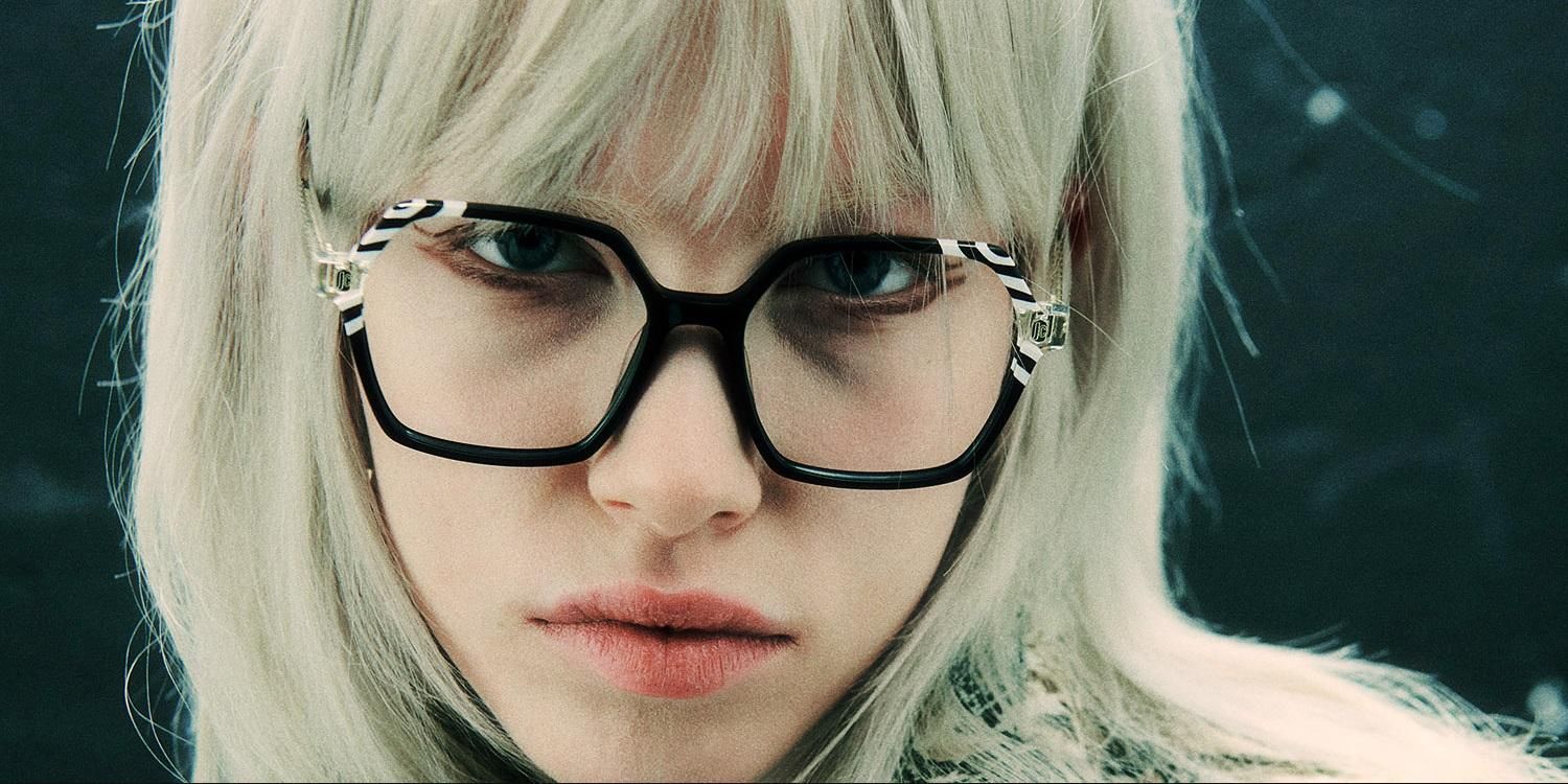 Una mujer con cabello rubio y gafas está mirando a la cámara.
