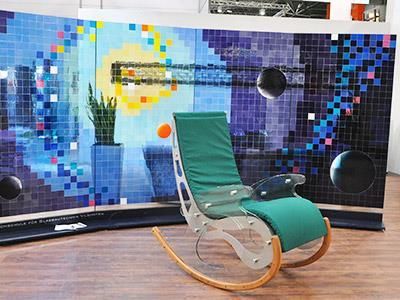 Vor einem Gemälde an der Wand steht ein grüner Schaukelstuhl.