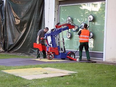 Ein Mann hebt mithilfe einer Maschine ein Glasfenster an.