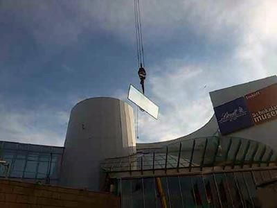 Ein Kran hebt ein großes Stück Glas vor ein Gebäude.