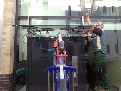 Ein Mann installiert mit einer Maschine ein Glasdach auf einem Gebäude.