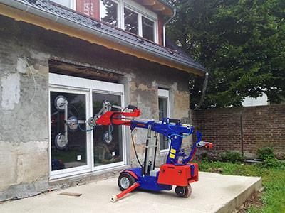 Vor einem Haus steht eine blau-rote Maschine.