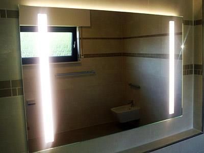 Ein Badezimmer mit einem großen Spiegel und zwei Lampen darauf.