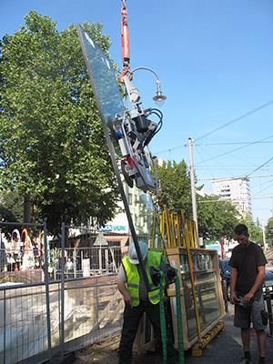 Ein Mann hebt mit einem Kran ein großes Stück Glas hoch.