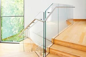 Eine Treppe mit einem Glasgeländer und Holzstufen in einem Haus.