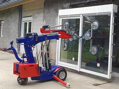 Eine blau-rote Maschine hebt ein Fenster vor einem Gebäude an.