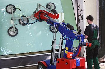 Ein Mann hebt mit einer Maschine ein großes Stück Glas an.