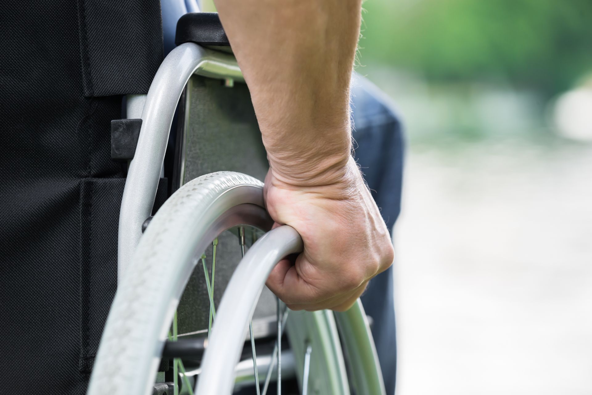 Personne en fauteuil roulant avec la main droite en train de faire avancer le fauteuil