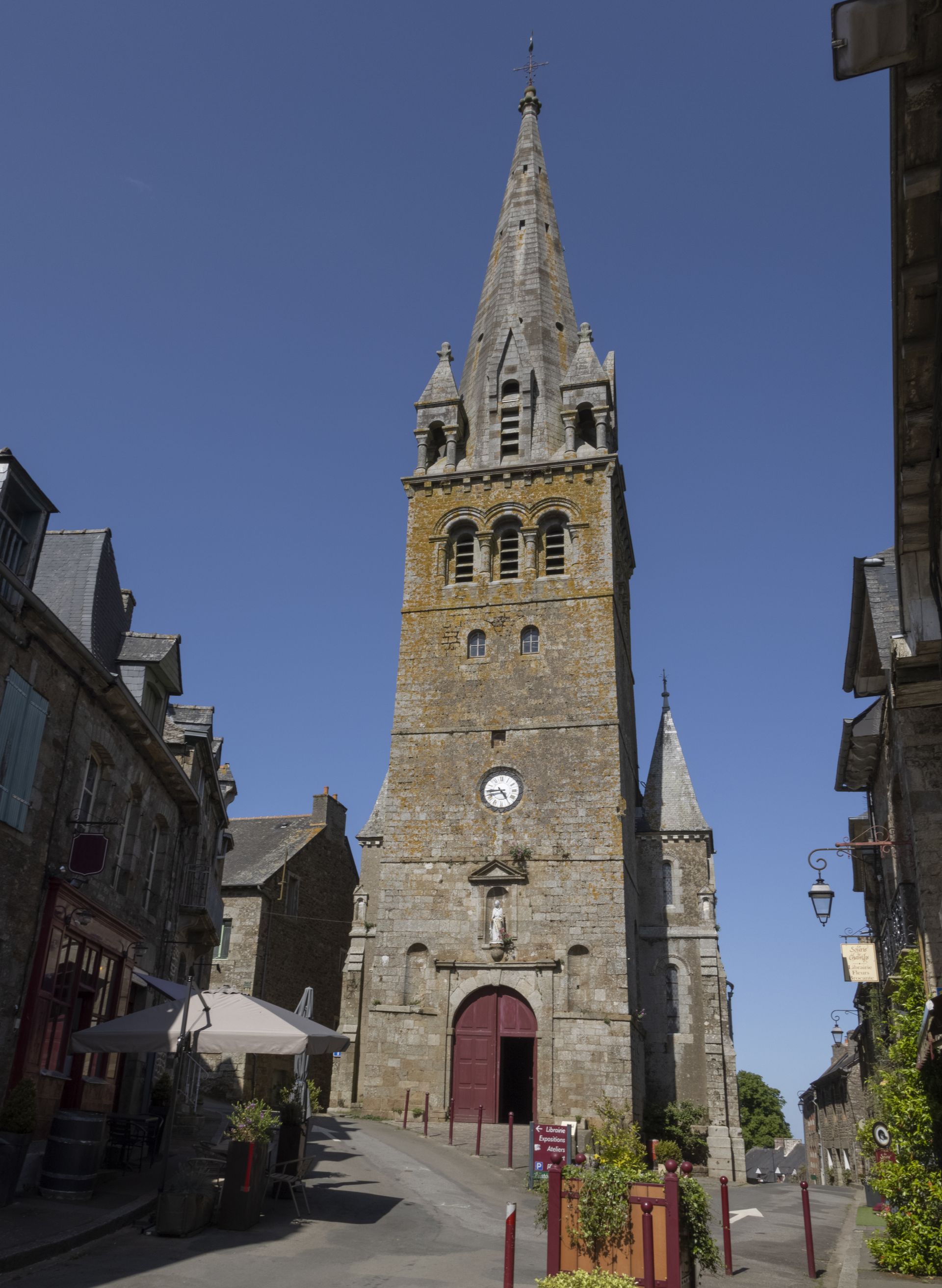 Église en pierre sur une petite place d'un bourg et route en patte-d'oie