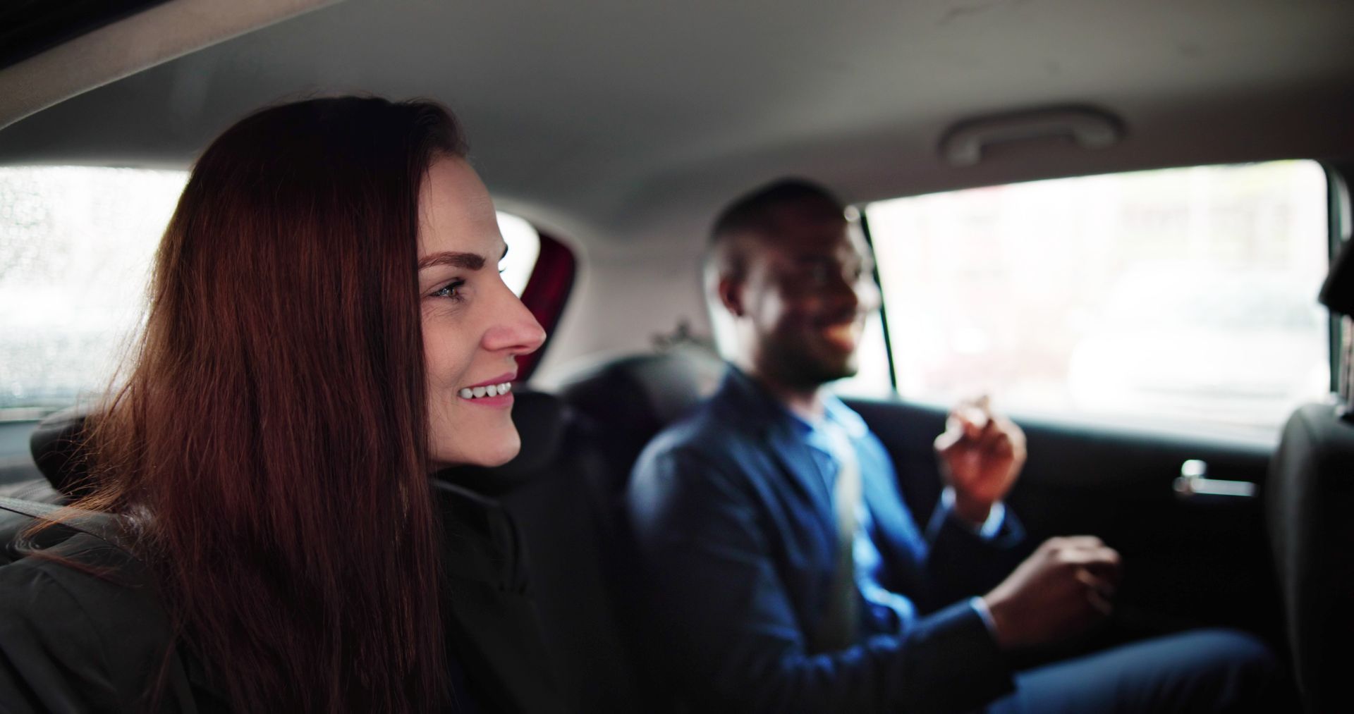 Un homme et une femme souriants, assis à l'arrière d'un véhicule.