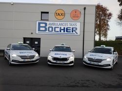 Trois taxis argentés stationnés devant un bâtiment de la compagnie de taxis et d'ambulances