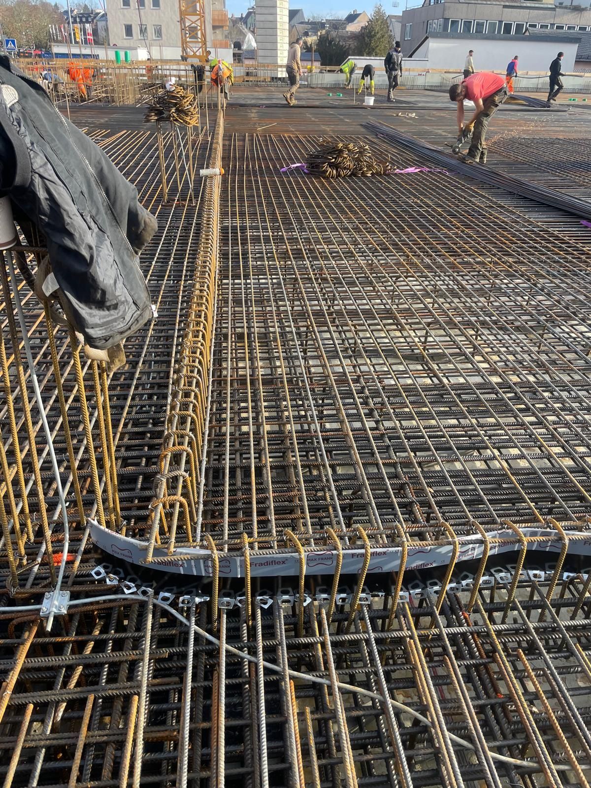 Arbeiter auf einer Baustelle montieren Stahlbewehrungsstäbe für eine Betonplatte.