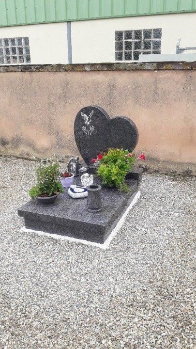 Une tombe en marbre avec des éléments en pierre et deux bouquets de fleurs