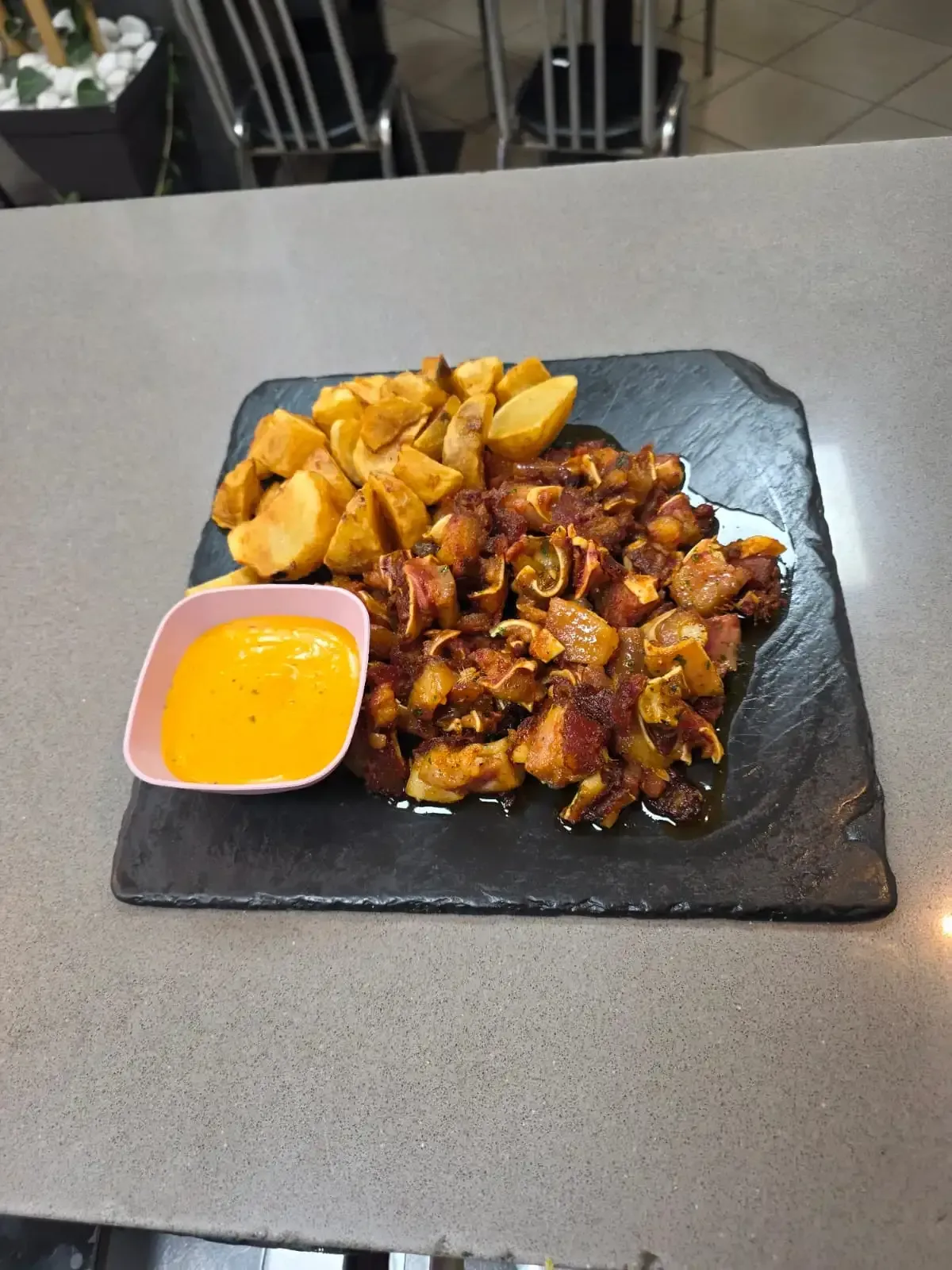 Plato individual de pollo con salsa y patatas gajo con una pequeña taza de salsa de naranja 