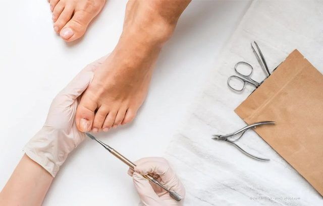 Eine Nageldesignerin trägt einer Kundin Nagellack auf die Fußnägel auf, die auf einem Spa-Handtuch liegen