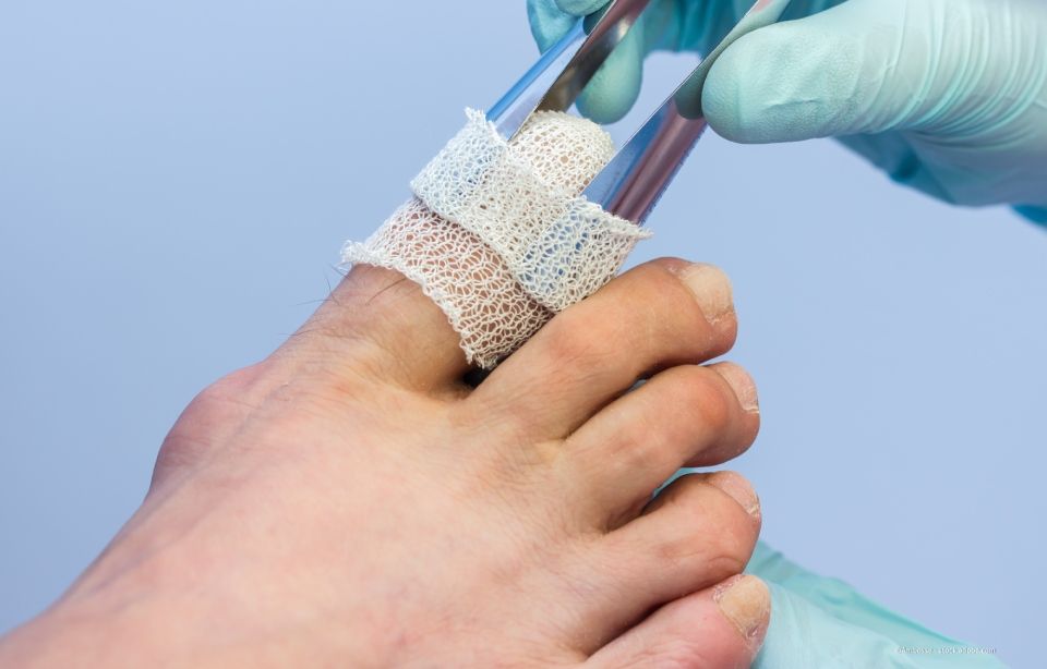Arzt massiert während einer Behandlungssitzung den Fuß eines Patienten