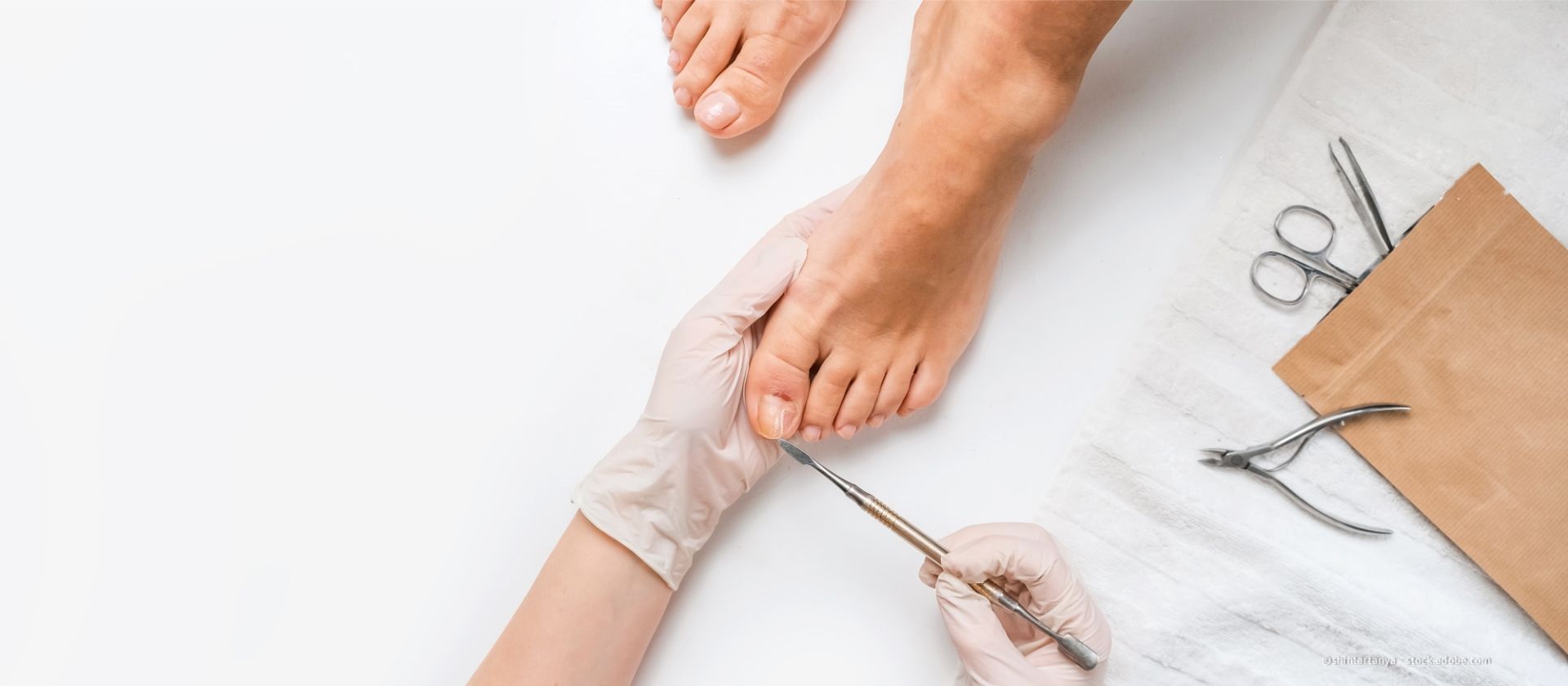 Eine Nageldesignerin trägt einer Kundin Nagellack auf die Fußnägel auf, die auf einem Spa-Handtuch liegen