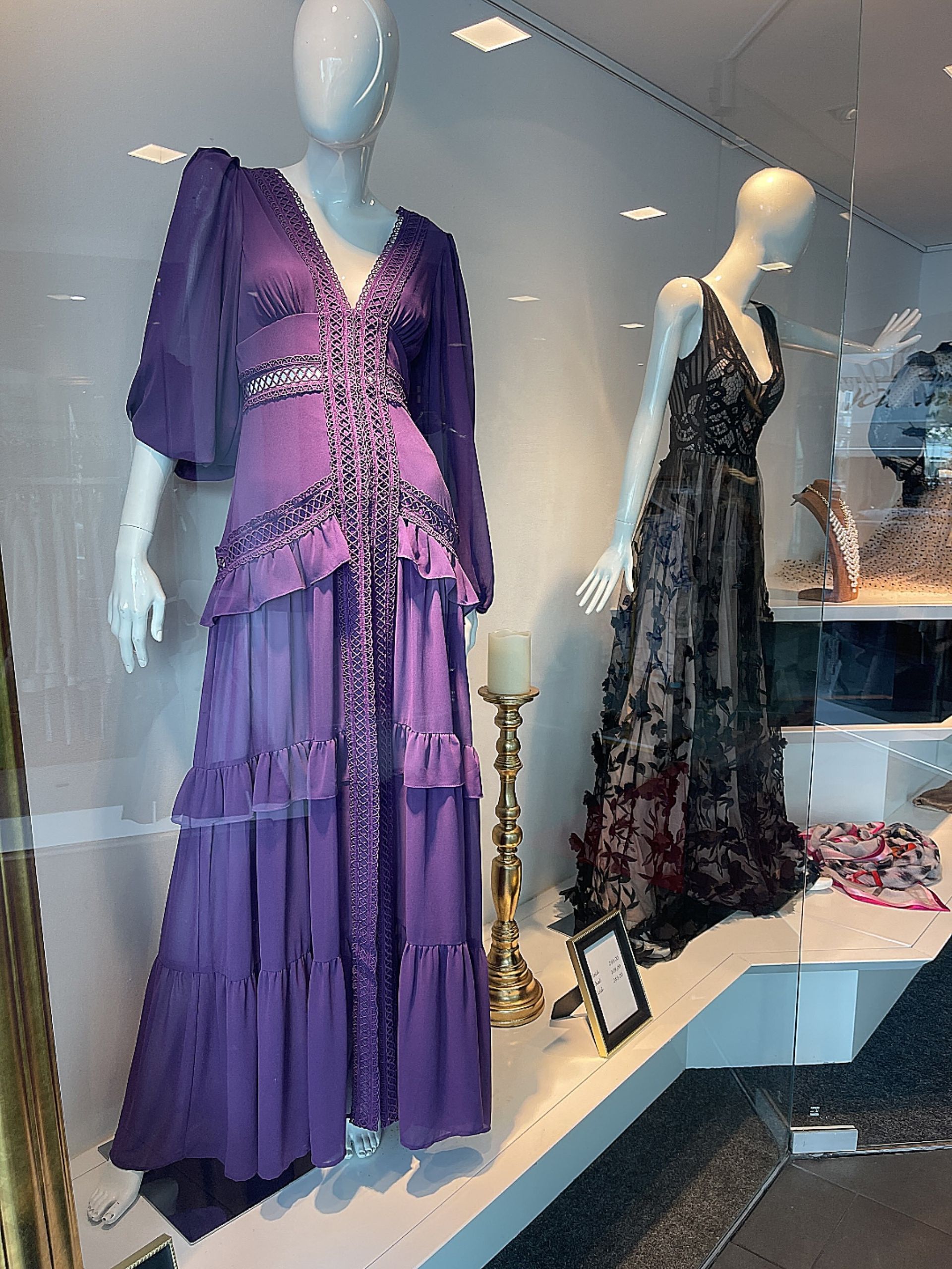 Eine Schaufensterpuppe mit einem lila Kleid steht neben einer Schaufensterpuppe mit einem schwarzen Kleid.