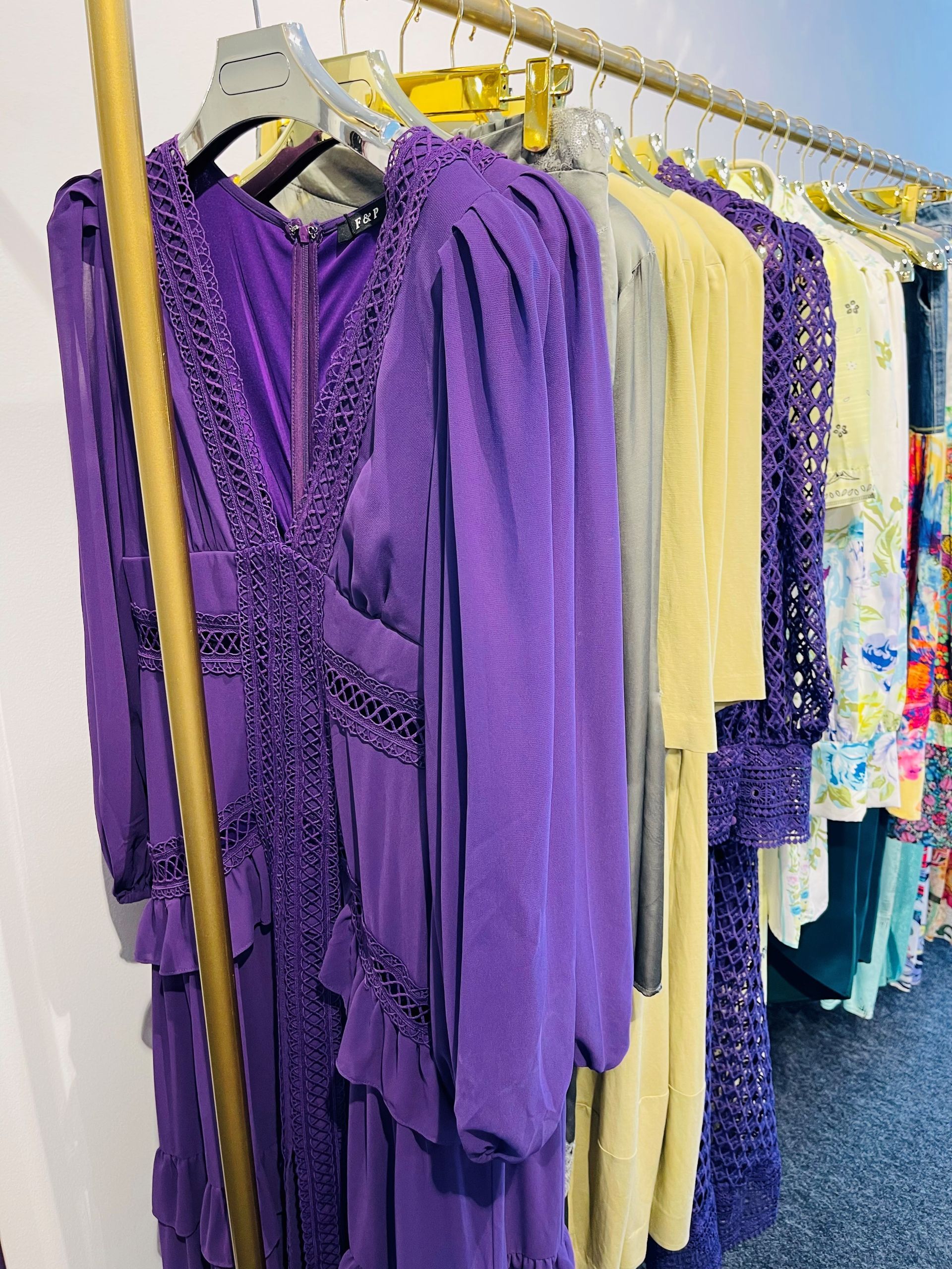 In einem Geschäft hängt eine Reihe lila Kleider an einer Stange.