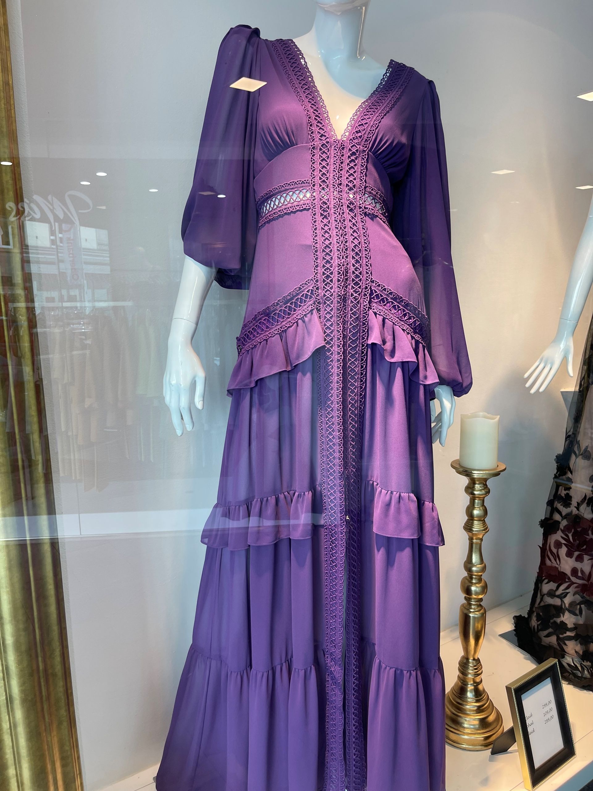 Eine Schaufensterpuppe trägt ein lila Kleid in einem Schaufenster.