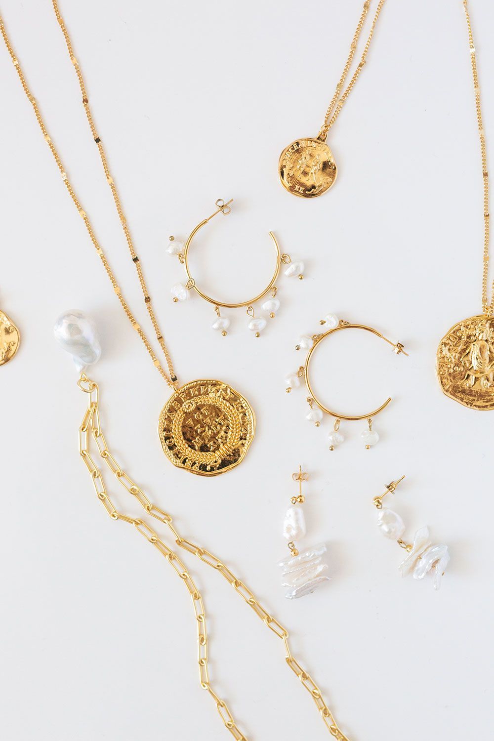 Verschiedene Goldschmuckstücke liegen auf einer weißen Fläche.