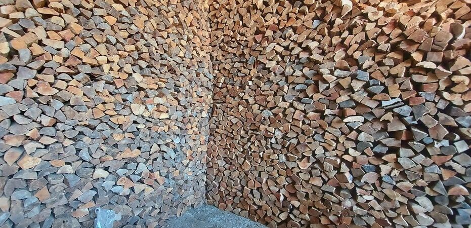 A lenha empilhada preenche o canto de uma sala, criando uma parede texturizada de pedaços de madeira.