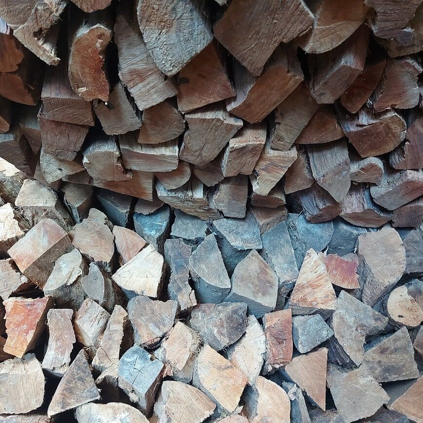 Pilha de lenha rachada, em vários tons de madeira.