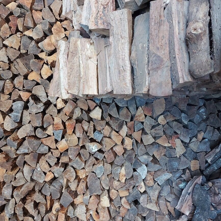 Pilha de lenha picada com variados tons de marrom e cinza.