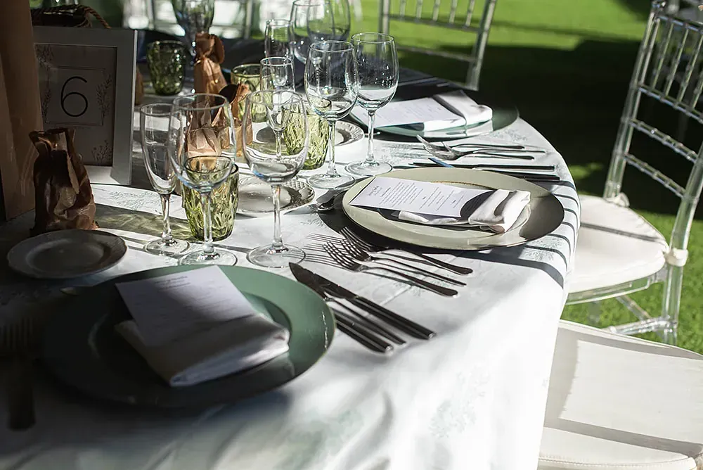 Una mesa puesta para una recepción de boda con platos, vasos y cubiertos.
