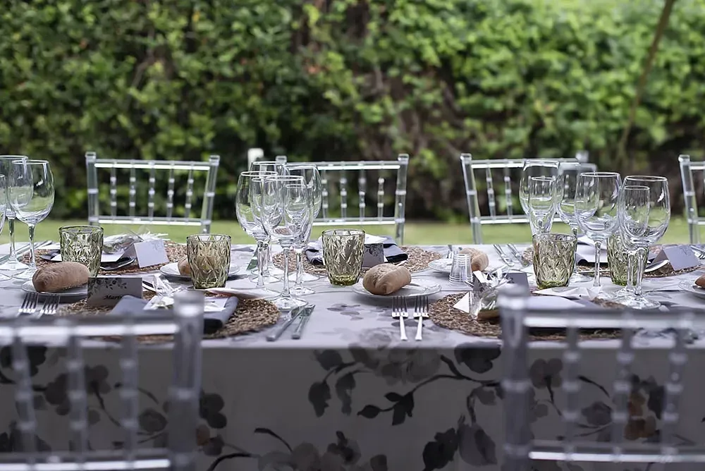 Una mesa puesta para una recepción de boda con platos, vasos y cubiertos.