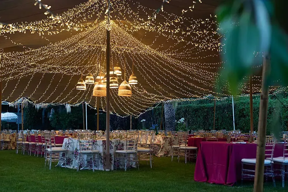 Una fotografía en blanco y negro de personas sentadas en mesas bajo una carpa.