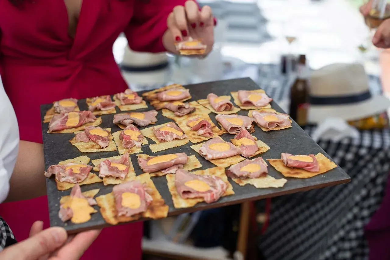 Una mujer con un vestido rojo sostiene una bandeja de comida.