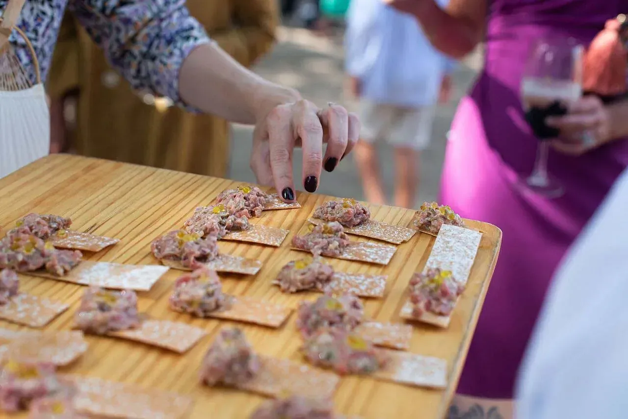 Una persona está alcanzando un trozo de comida en una mesa de madera.