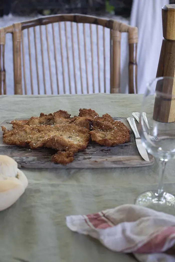 Una mesa de madera con un plato de comida y una copa de vino.