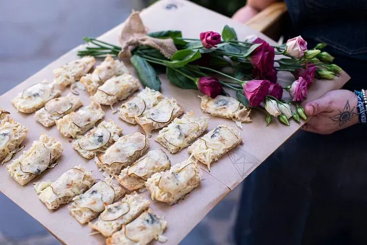 Una persona sostiene una bandeja de comida y flores.