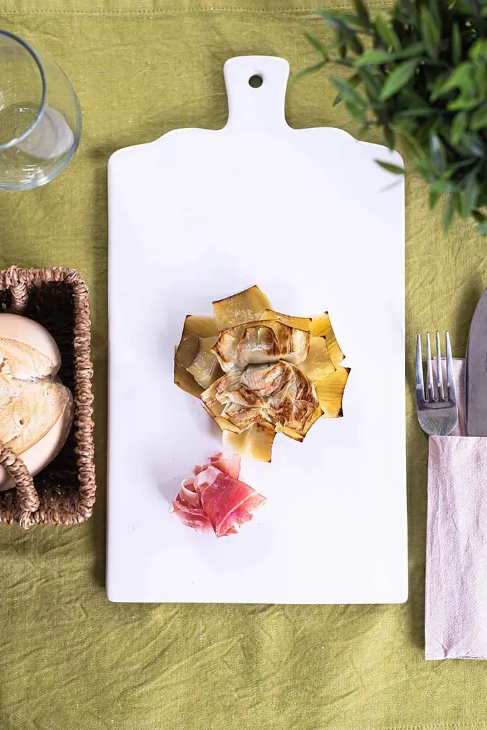 Una tabla de cortar blanca con un trozo de comida encima.