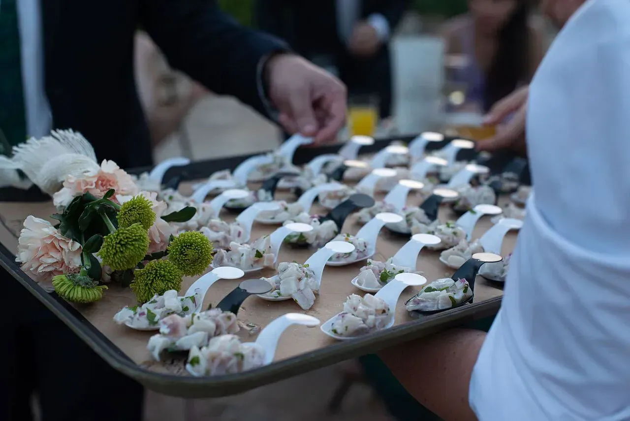 Una persona sostiene una bandeja de comida con cucharas sobre ella.