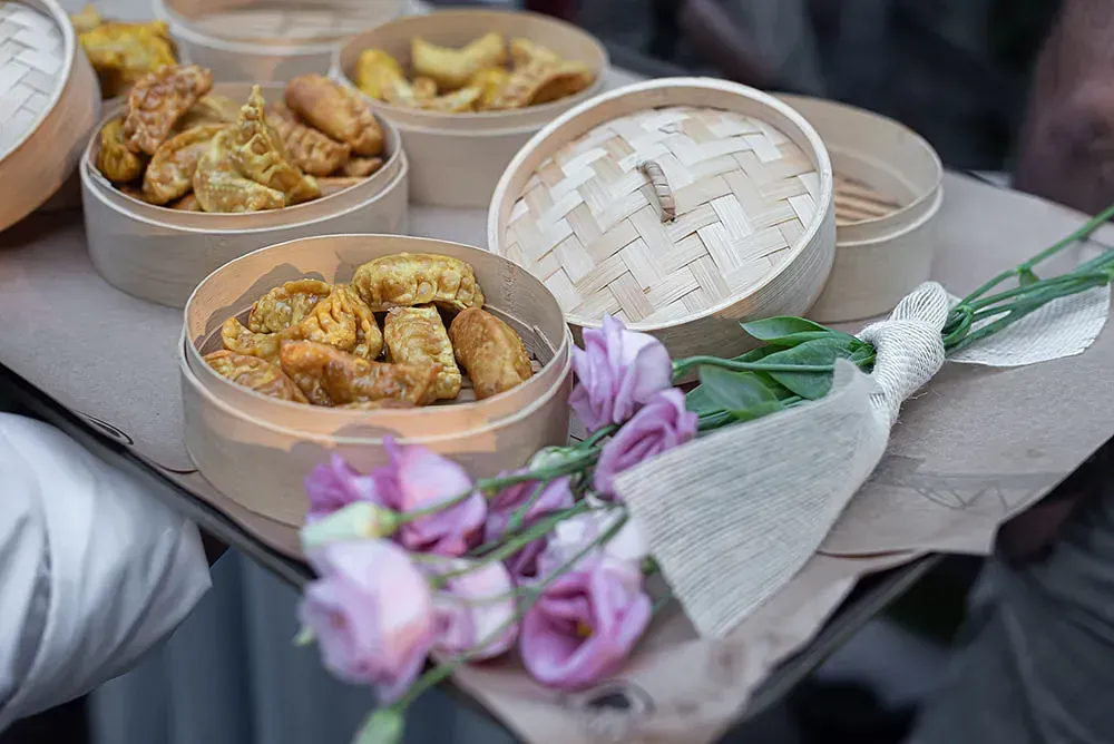 Una persona sostiene una bandeja de comida y flores.