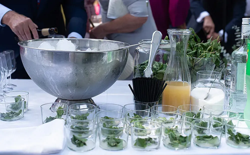Una mesa con un bol de hielo y vasos llenos de hojas de menta.