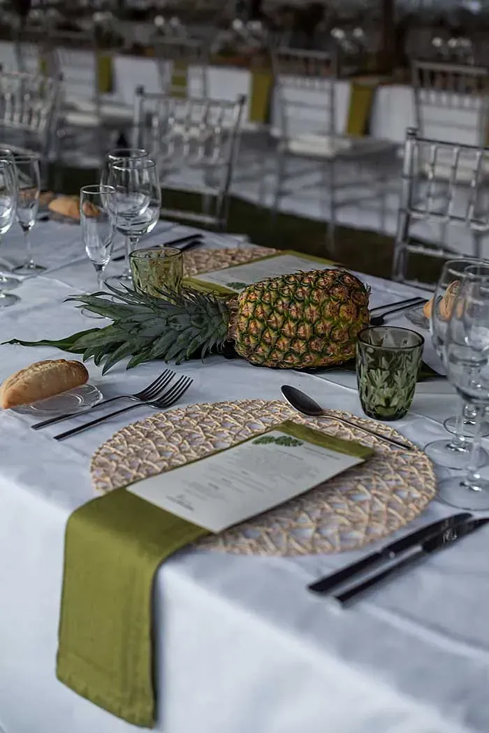 Una mesa preparada para una recepción de boda con una piña encima.