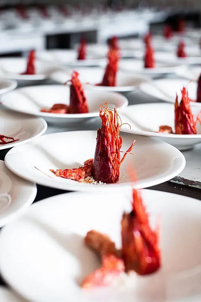 Una fila de platos blancos cubiertos con comida roja sobre una mesa.