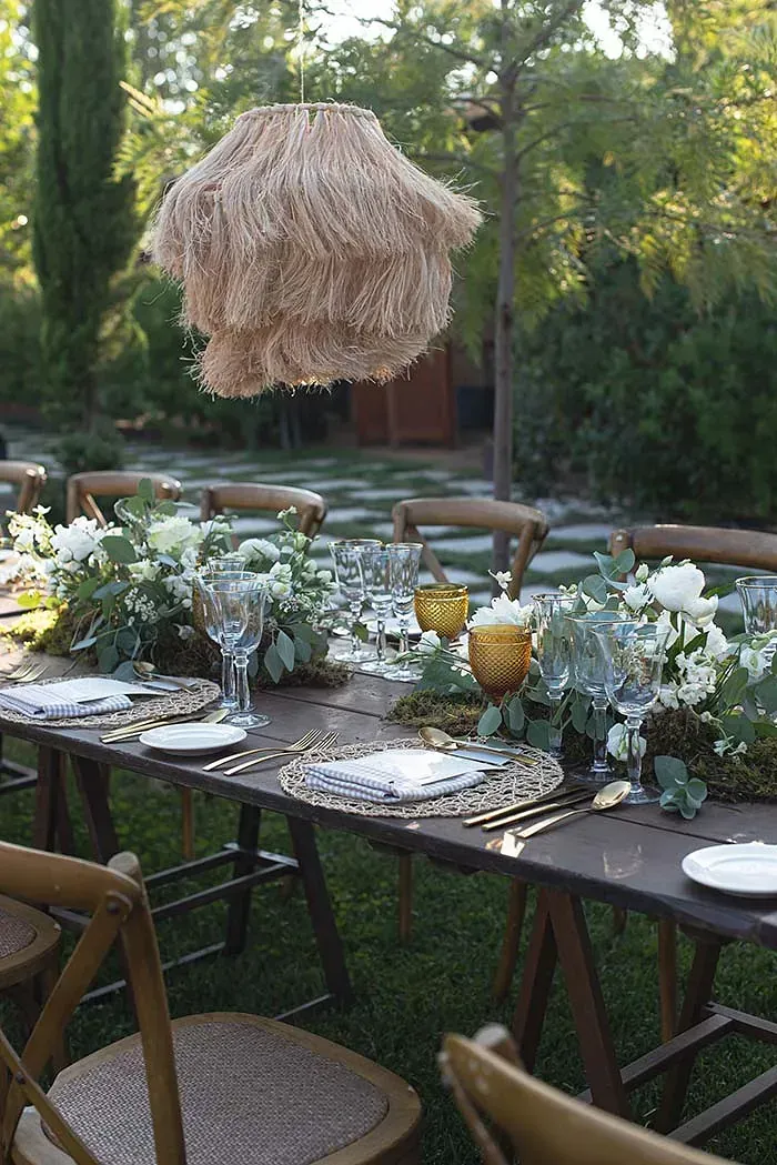 Una mesa larga con platos, cubiertos y flores sobre ella.