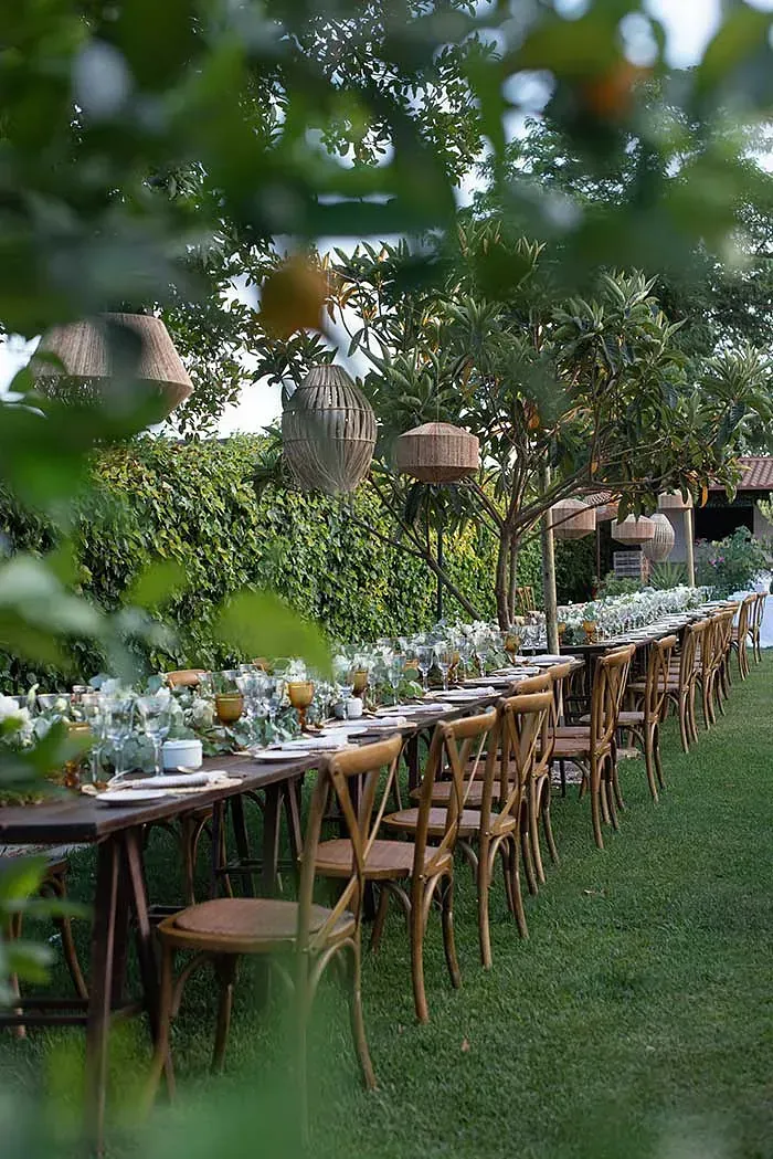 Una larga fila de mesas y sillas colocadas sobre un exuberante campo verde.