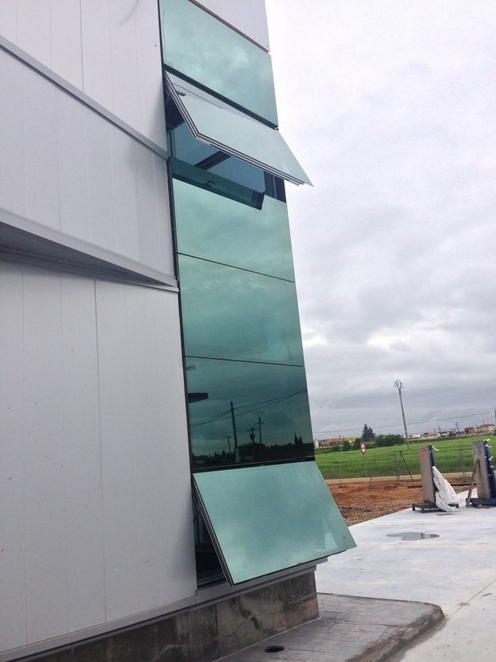 Edificio moderno con una alta columna de vidrieras, algunas abiertas. Vista exterior en un día nublado.