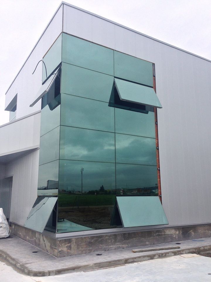 Edificio moderno con ventanas de vidrio tintado verde. Algunas ventanas están abiertas.