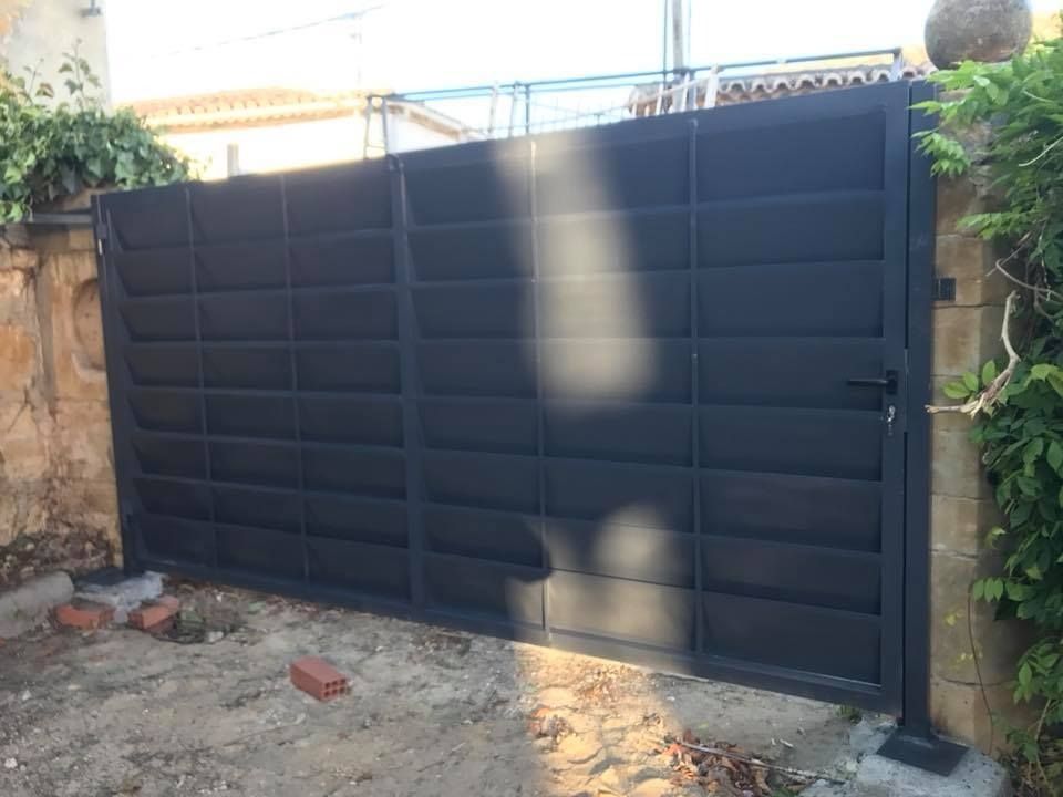 Puerta de entrada de metal negro en un patio, cerrada.