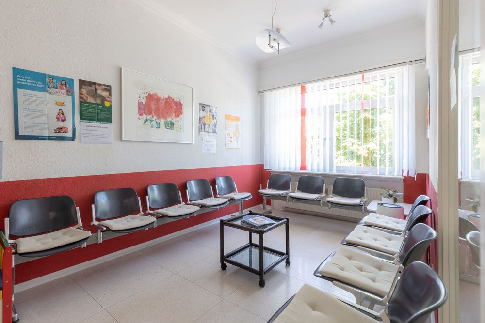 Ein Wartezimmer mit Stuhlreihen und einem Couchtisch.