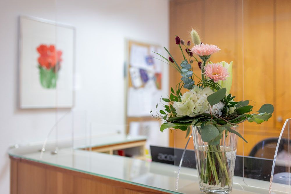 Auf einer Glastheke steht eine Vase mit Blumen.