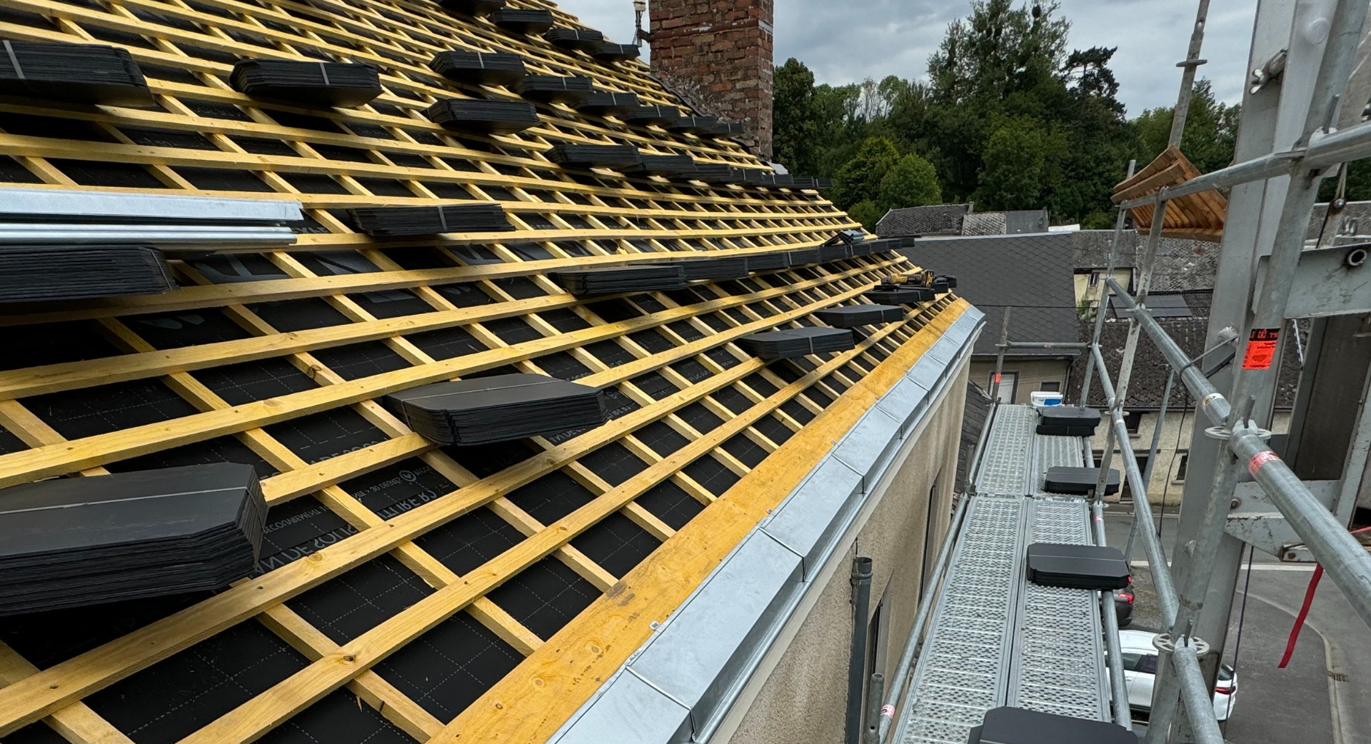 Un toit est en cours de construction sur un bâtiment avec un échafaudage autour.